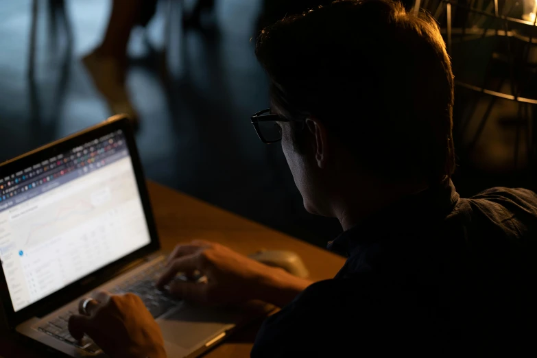 a man in glasses working on his laptop