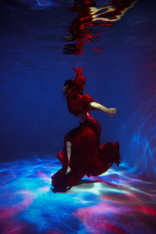 a woman in a red dress and other colored lights underneath water