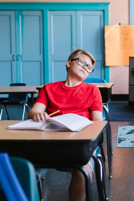 a young male wearing glasses while sitting at his desk