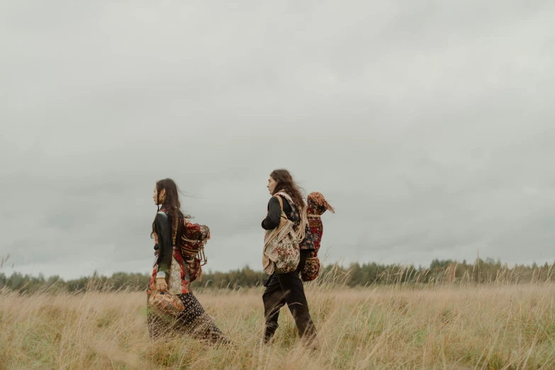 two young ladies are in a field walking and talking