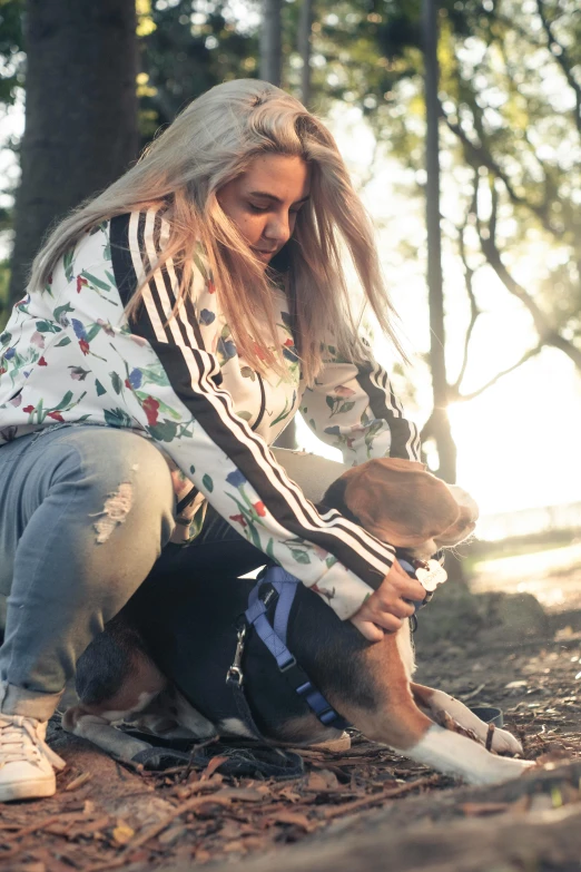 a woman sitting on the ground and petting a dog