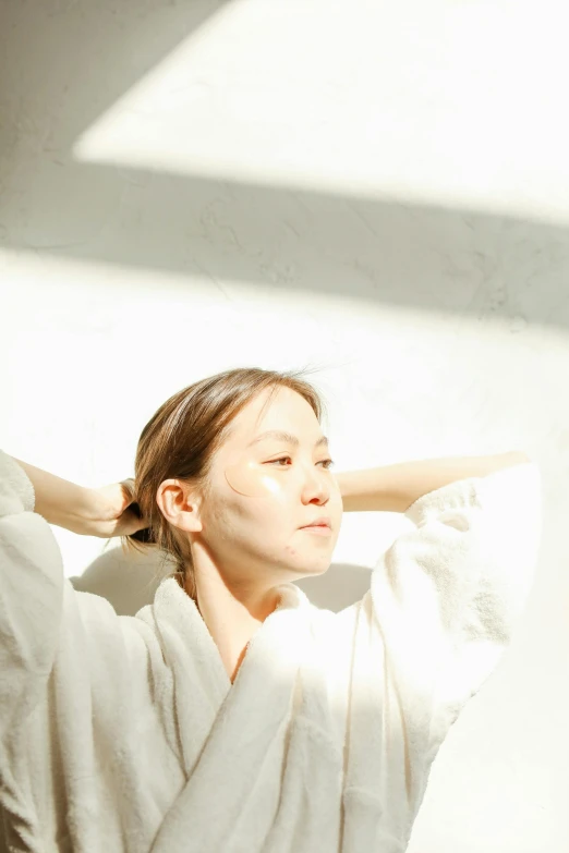 a woman wearing a robe holding her hair behind her head