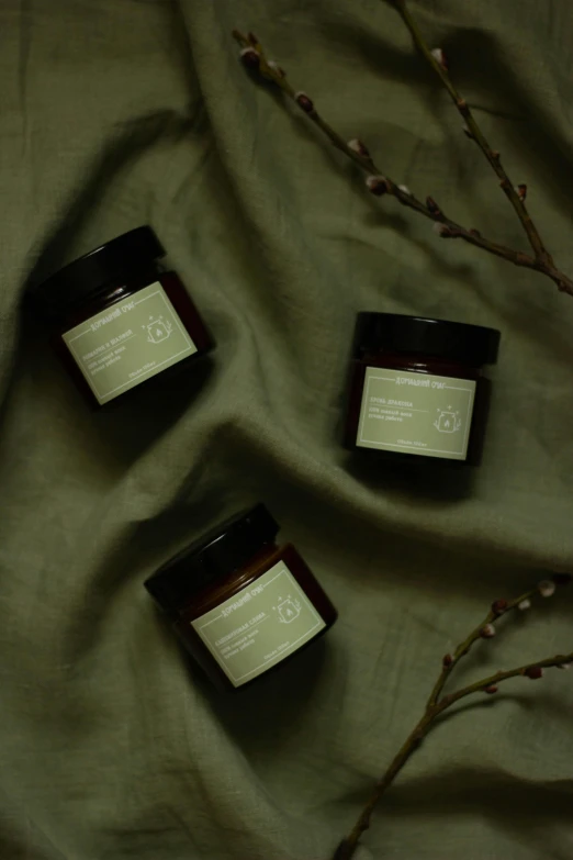 three jars sit next to each other on a green cloth