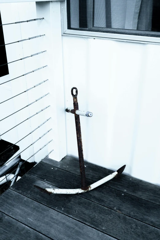 an old anchor propped up on a wooden porch