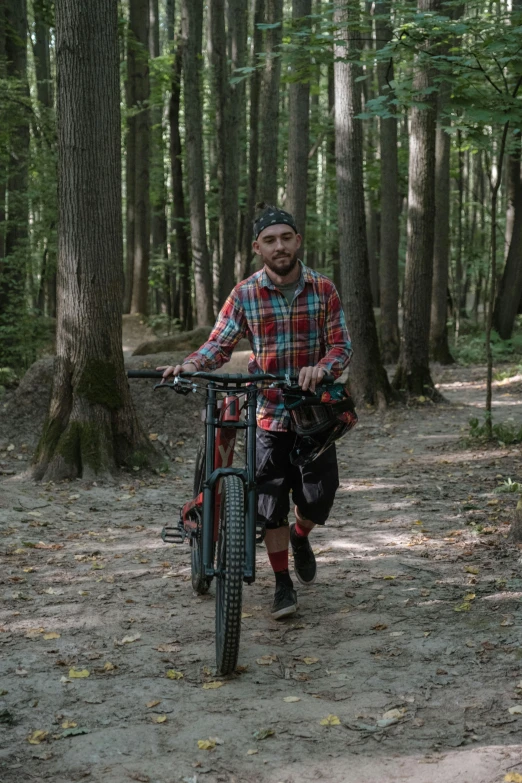 a man with a bicycle walks through a forest