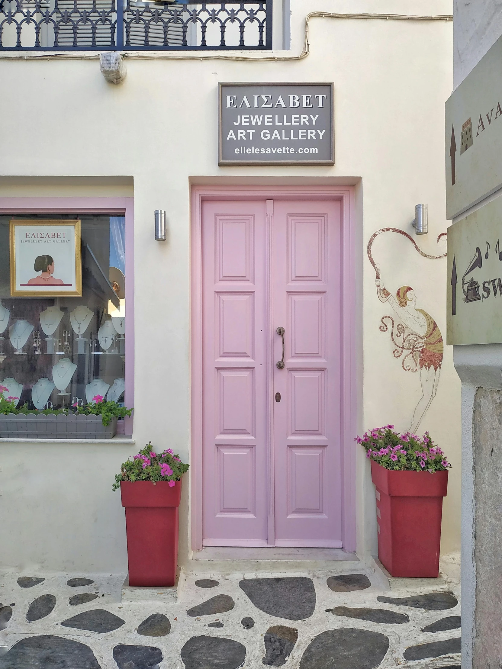 an outdoor shop with potted flowers and two pink doors