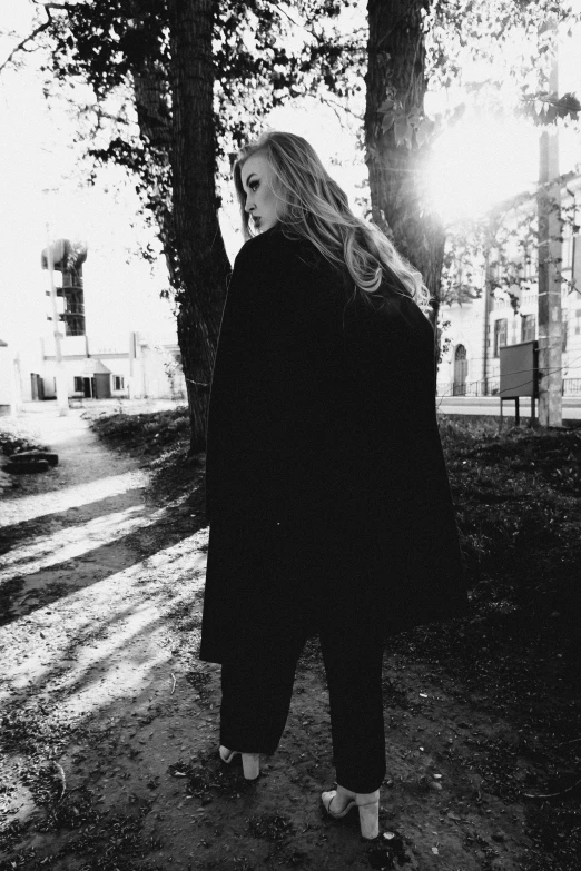 a woman in black jacket standing near trees