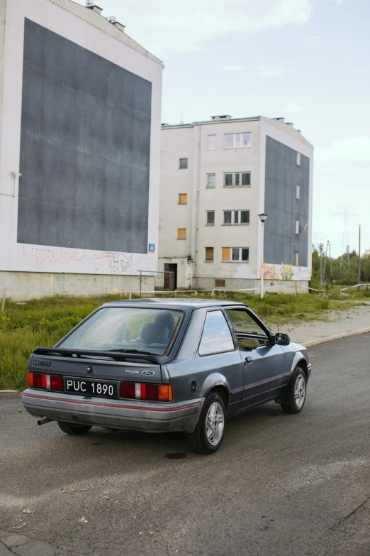 an old grey car is parked in the middle of the road