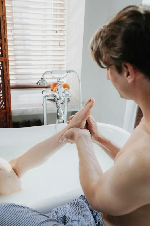 a man bathing in a tub holding his hand