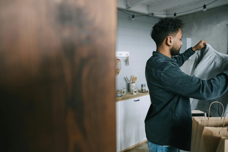 a man holding a coat over his sweater while hanging it