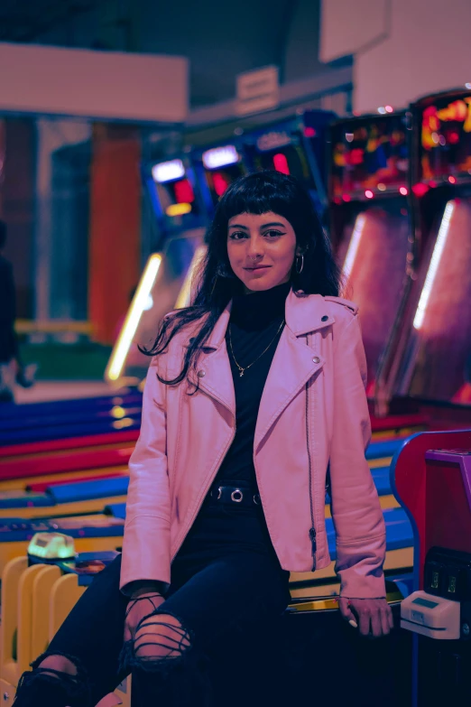 a woman sitting on a bench near colorful bowling machines