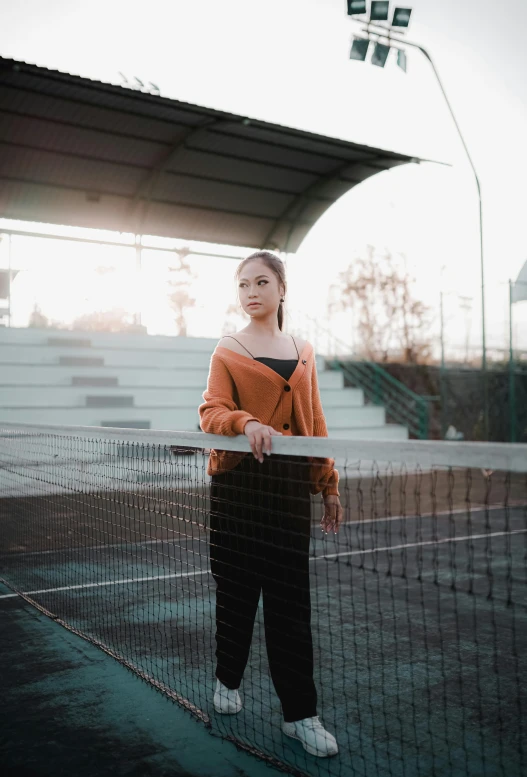 a person standing by a fence with a racket