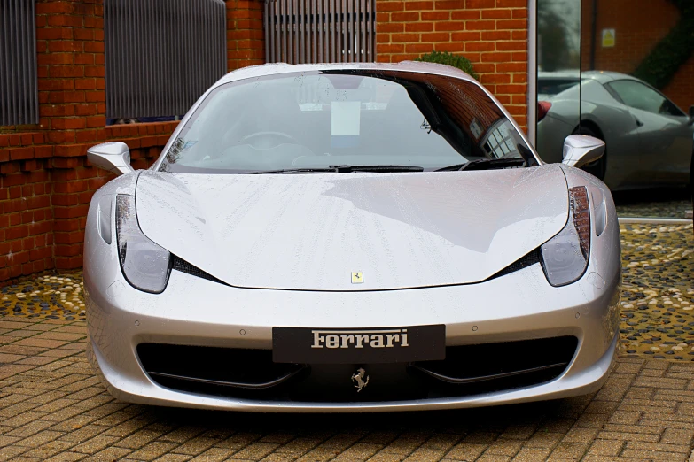 a silver sports car parked next to a brick wall