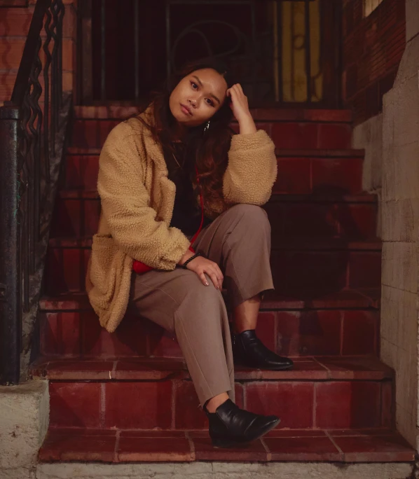 a woman sitting on the steps wearing a coat