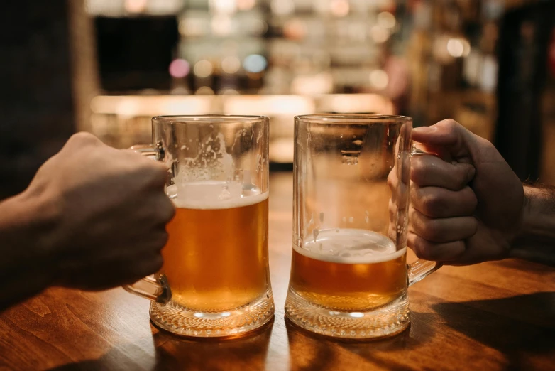 two mugs of beer and a person reaching to it