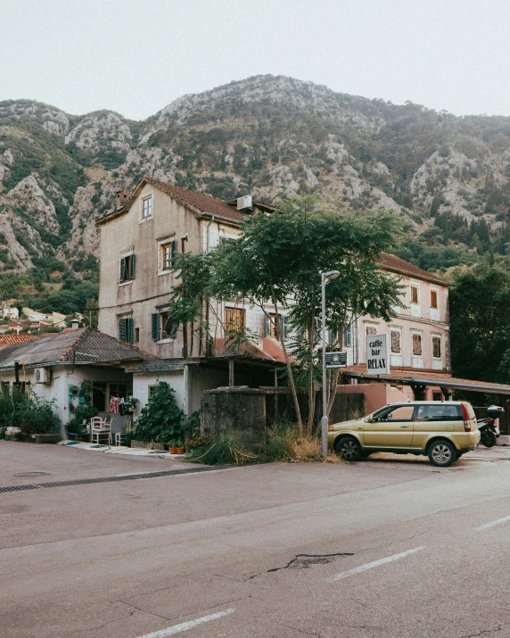 there is an old yellow car parked outside of a building