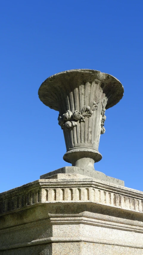 a very old looking concrete urn in front of a blue sky