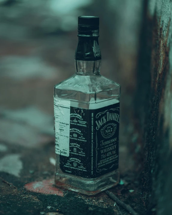 an empty bottle is sitting on a grungy surface