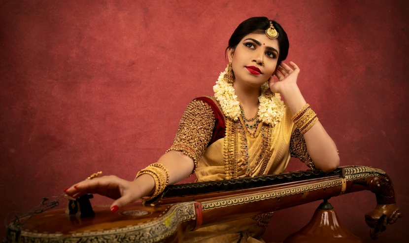 a woman in a traditional indian garb leaning on a piano