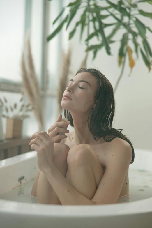 a young woman sitting in a bath tub with her eyes closed