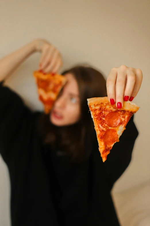 a girl holding a piece of pizza on her hands