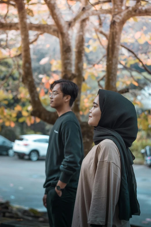 two young people stand together in front of the trees