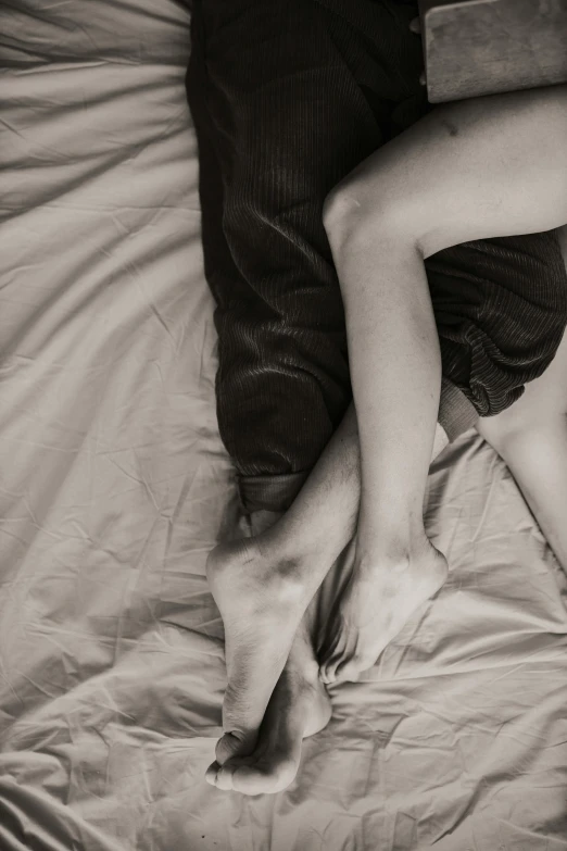 man and woman lay down in bed with their legs crossed