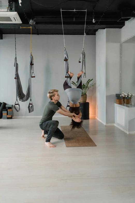 two men doing aerial yoga in a gym