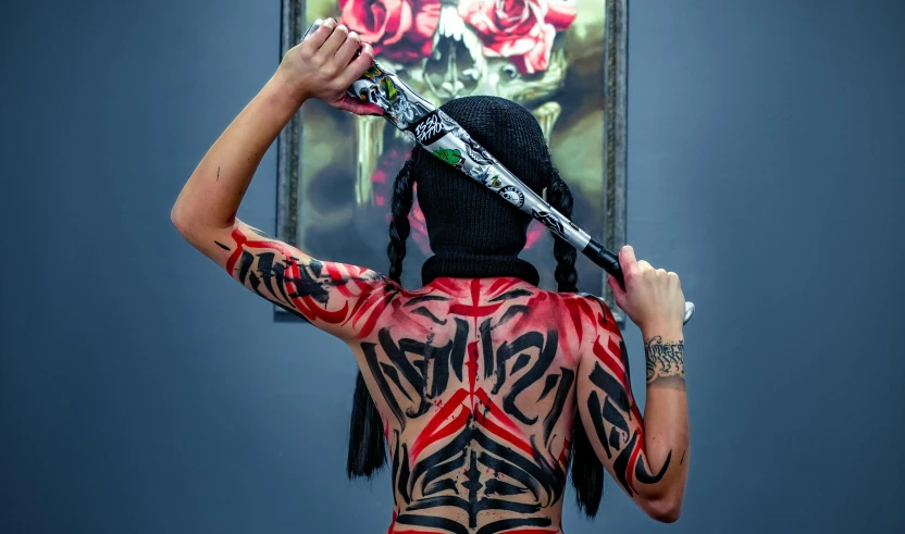 woman with large tattoo on her body holds a pair of scissors over her head