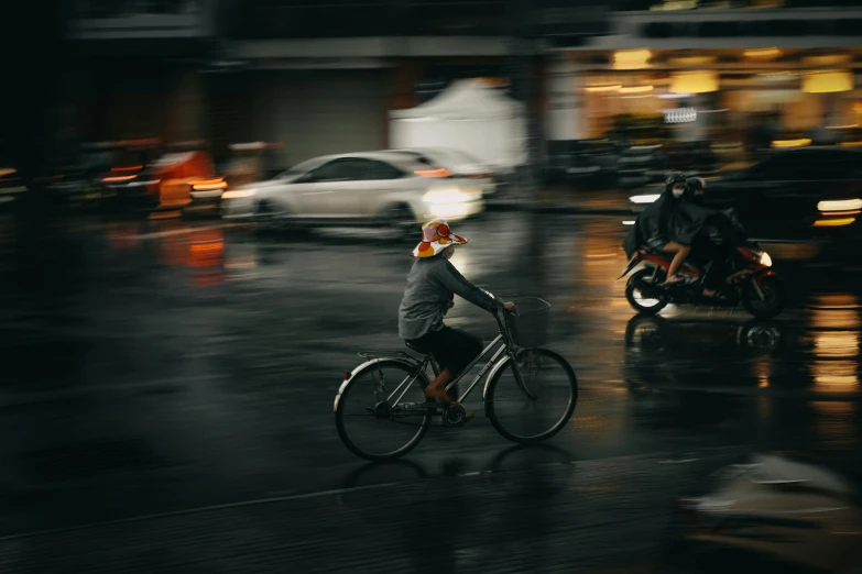 a man rides his bike through the street on a rainy day