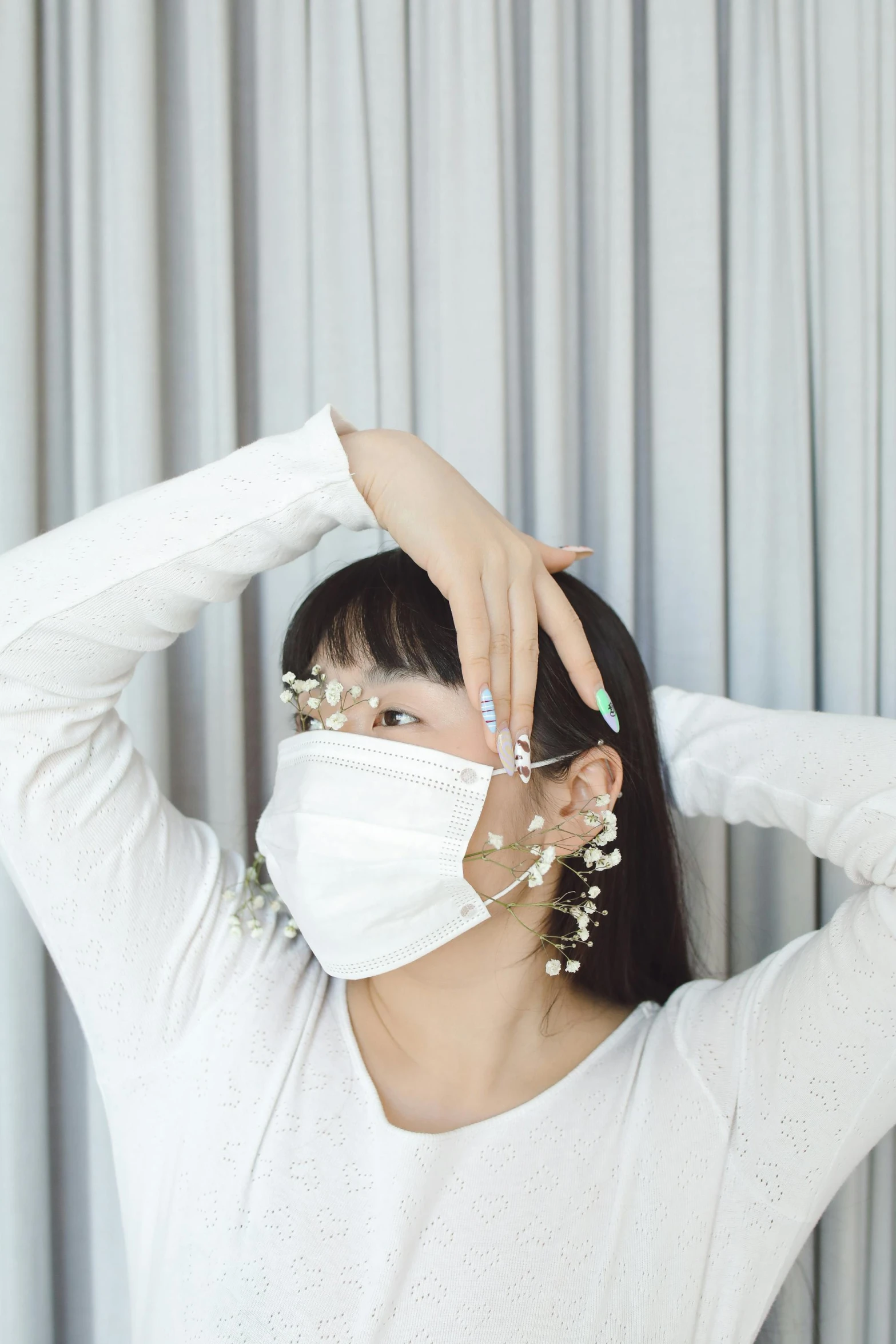 woman in white top wearing face mask, pulling up hair