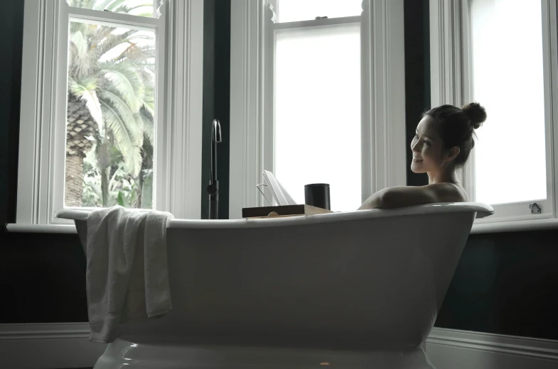 a woman relaxing in a bathtub surrounded by windows