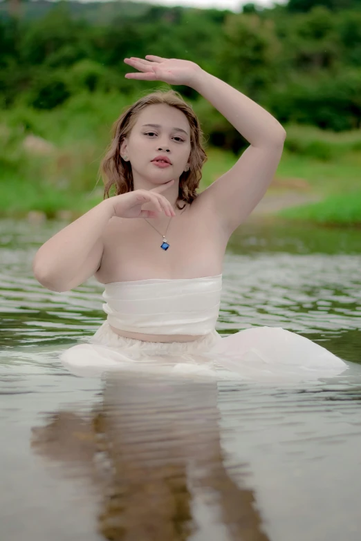 a girl sitting in water holding her hand over her face