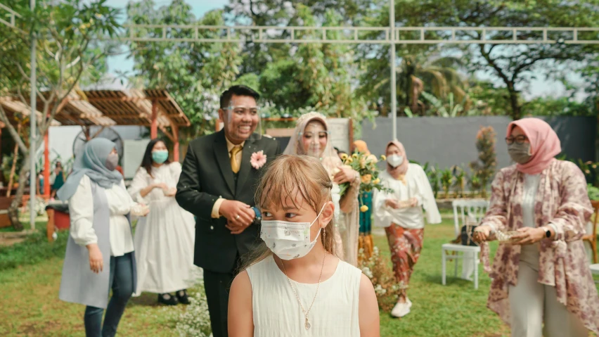 a girl at a wedding is wearing a face mask