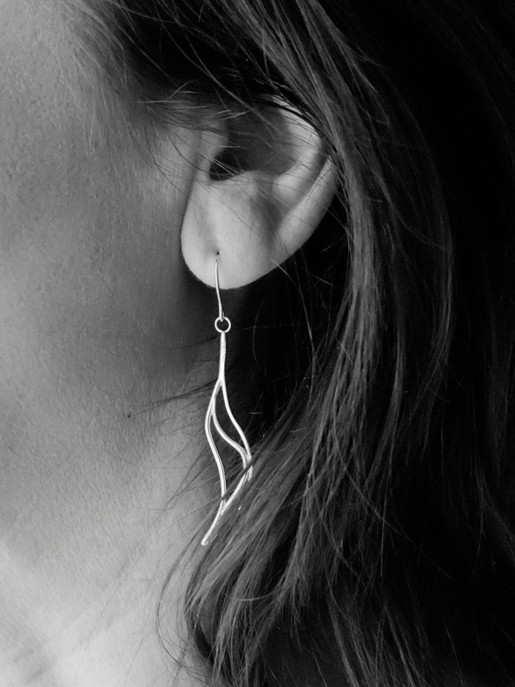 a girl wearing earings with a silver colored ear