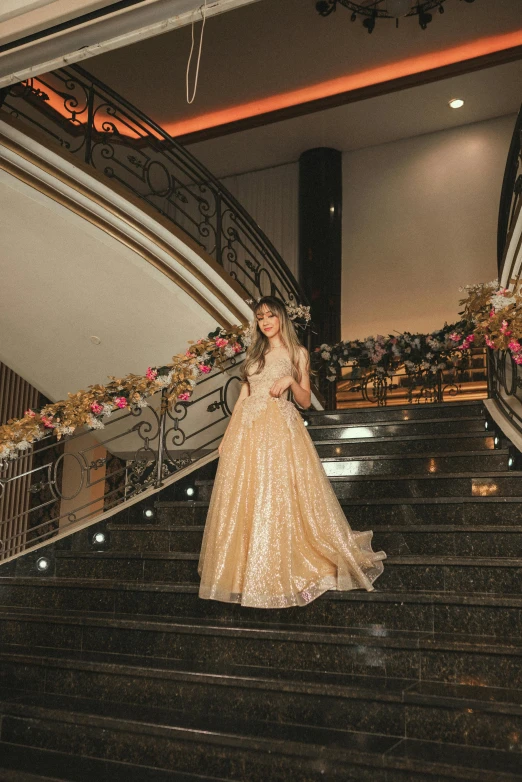 a woman in a golden dress on the staircase of a building
