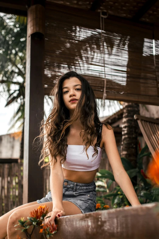 a girl in a white crop top standing next to an orange flower