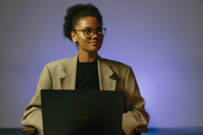 a black woman sitting in front of a laptop computer