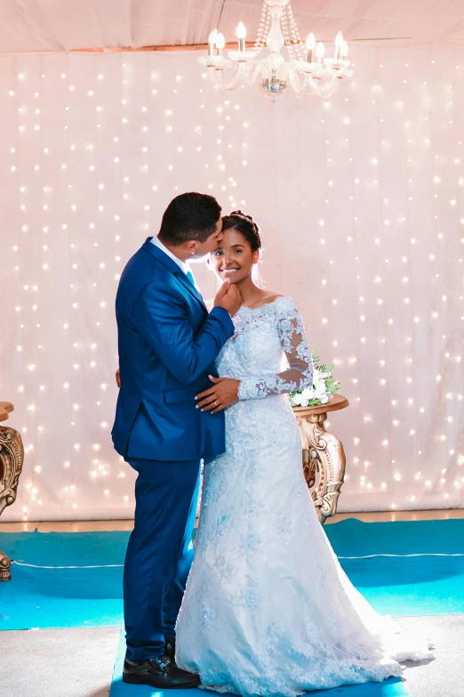 a couple holding each other in front of a chandelier