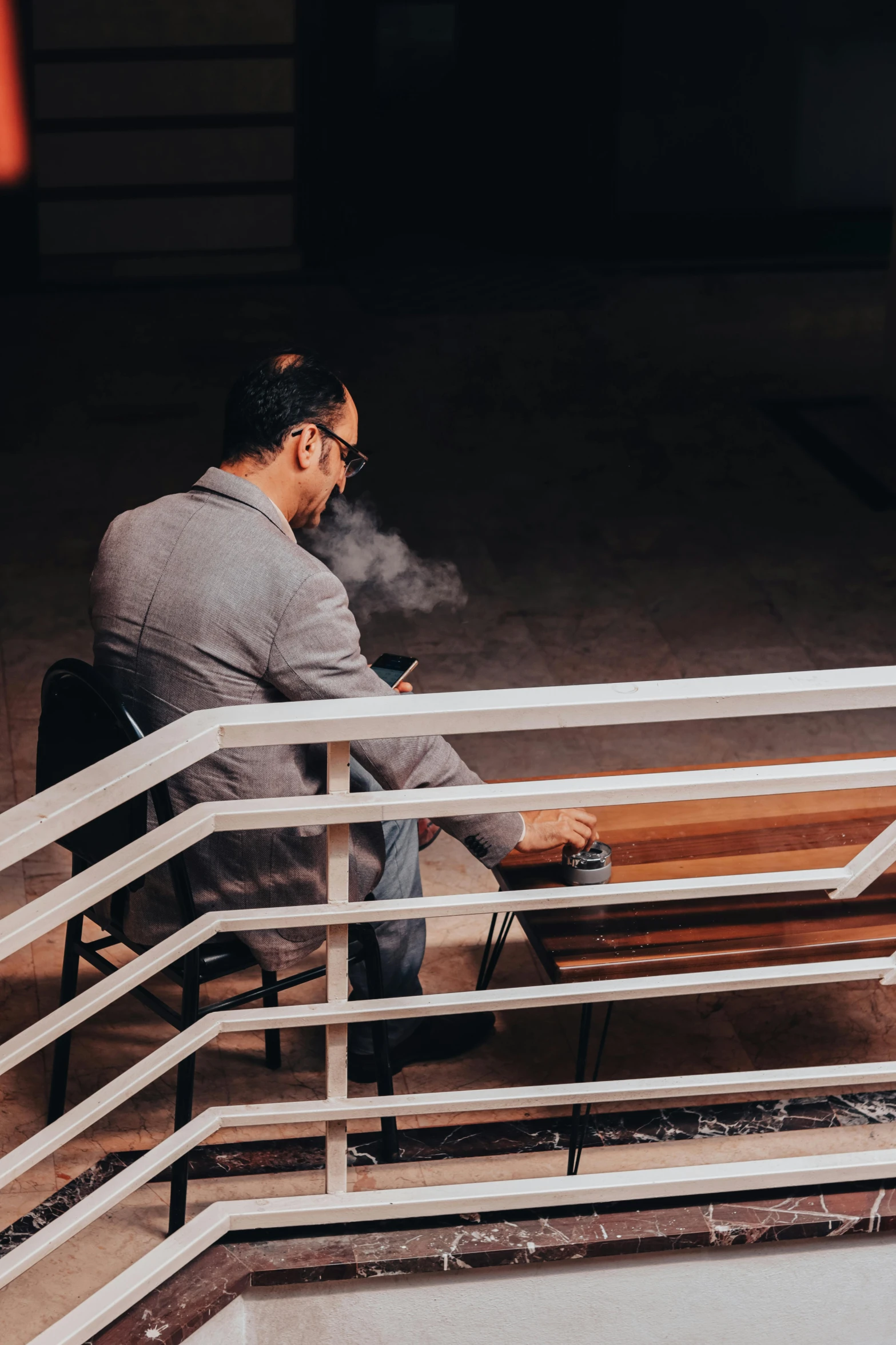 man seated on wooden bench holding cell phone