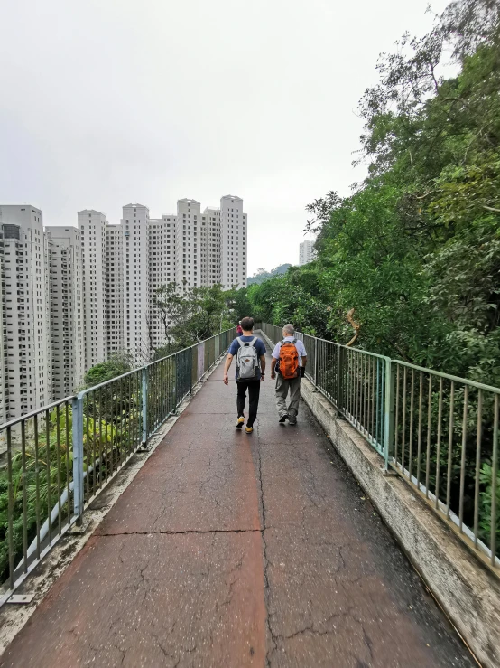 people walk across a bridge in front of tall buildings