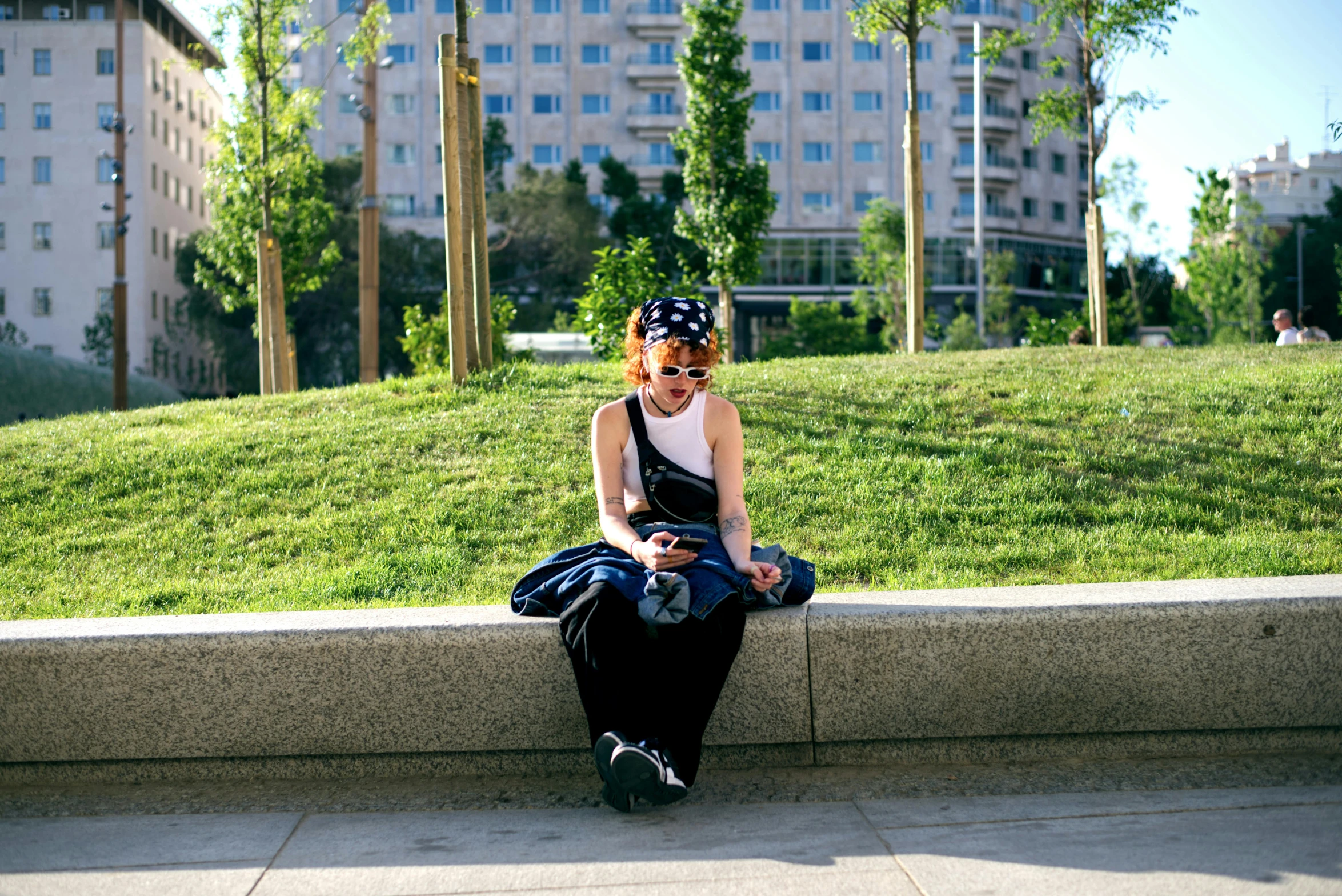 a woman sitting on a ledge near the grass