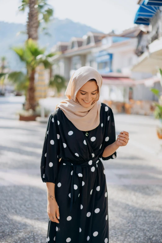 a woman standing on the street looking down at her hand