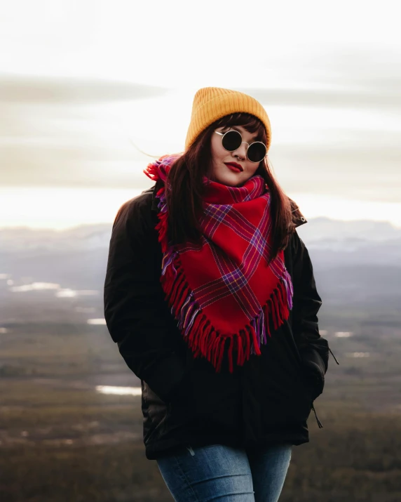 a woman in black jacket wearing red scarf and jeans