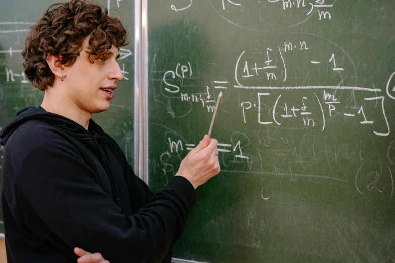 a male in a black shirt writing on a chalkboard