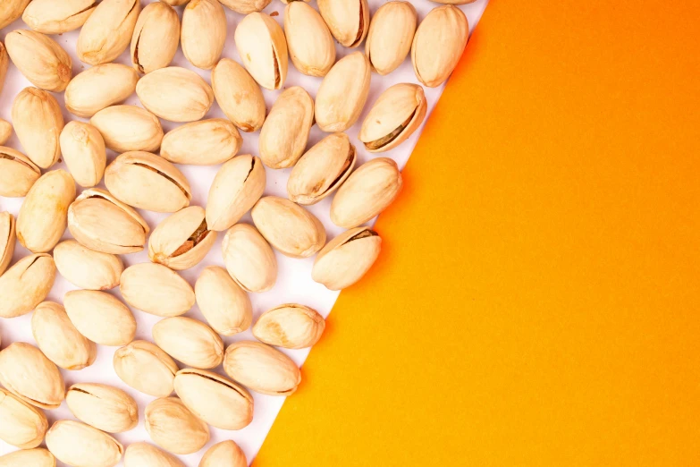 a close - up image of nuts spilling onto an orange background