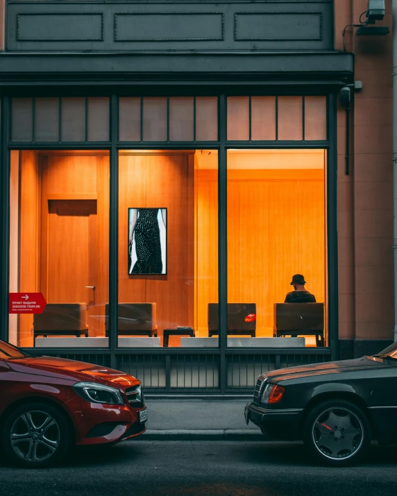 two parked cars sit in front of an office window