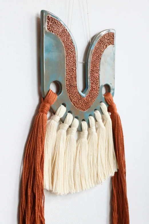 a wooden and painted sculpture with tassels and beads