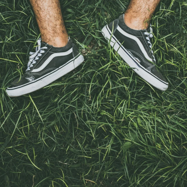 a man is standing in some grass with his legs crossed