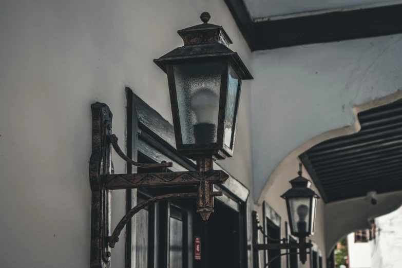 a lamp hanging on the side of a white building